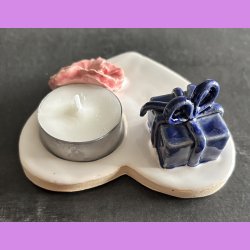 Fyrfadsholder med blomst og gave.