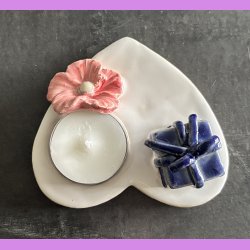 Fyrfadsholder med blomst og gave.