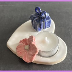 Fyrfadsholder med blomst og gave.