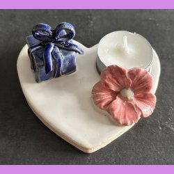 Fyrfadsholder med blomst og gave.