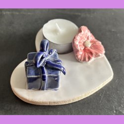 Fyrfadsholder med blomst og gave.