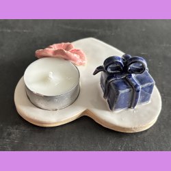 Fyrfadsholder med blomst og gave.