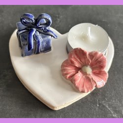 Fyrfadsholder med blomst og gave.