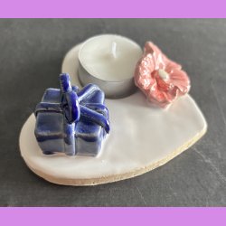 Fyrfadsholder med blomst og gave.